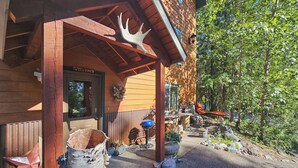 A wooden lodge with a covered porch, a welcome sign, and a barbecue grill. - Secluded Mtn Retreat w/ Resort Perks in Whitefish! (Whitefish)