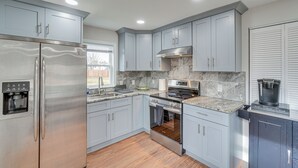 A modern kitchen with stainless steel appliances, grey cabinetry, and a marble backsplash. - Walk to Leesburg Historic District: Family Retreat (Leesburg)
