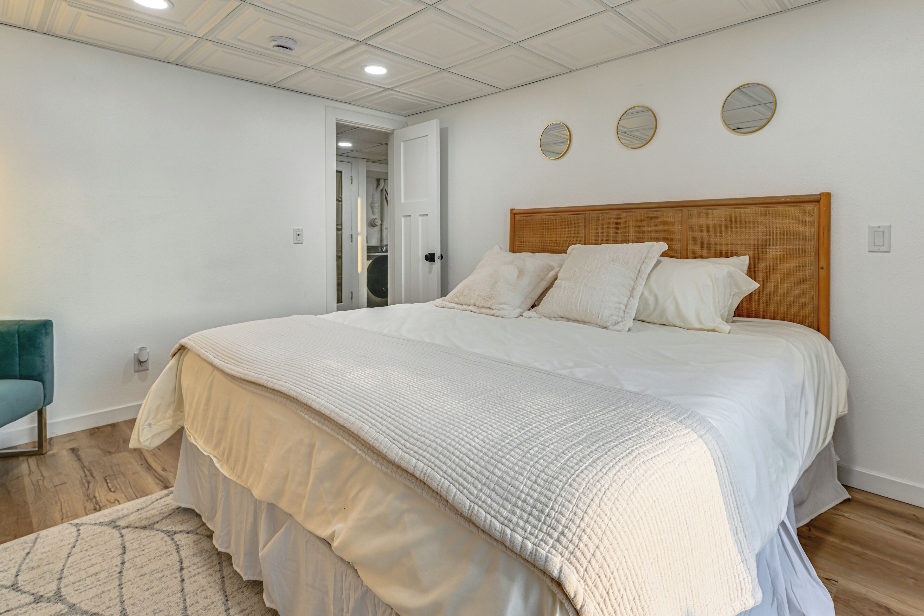 Un dormitorio con una cama grande, un cabecero de madera y una pared blanca con tres espejos redondos.