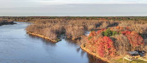 A river with a house on the right bank, surrounded by autumn foliage.