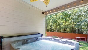 A hot tub in a covered outdoor area with a view of a wooded backyard. - Patio Oasis w/ Hot Tub! Lake Livingston Estate (Coldspring)
