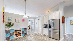 Une cuisine moderne avec des meubles blancs, un réfrigérateur en acier inoxydable et un plancher en bois.
