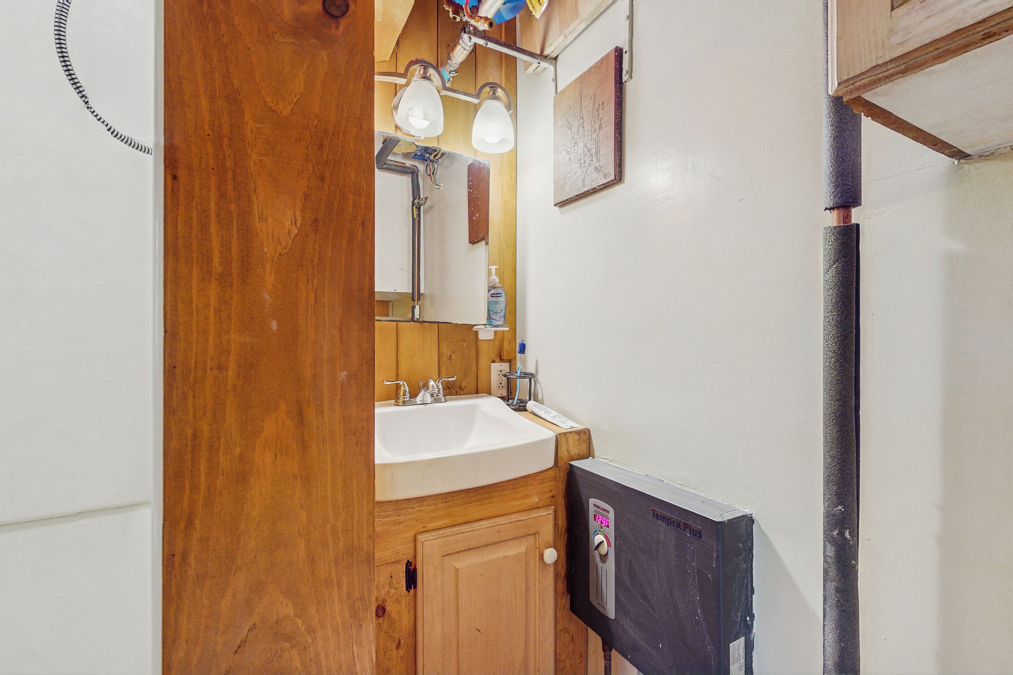 A bathroom with a wooden vanity, a white sink, and a mirror.