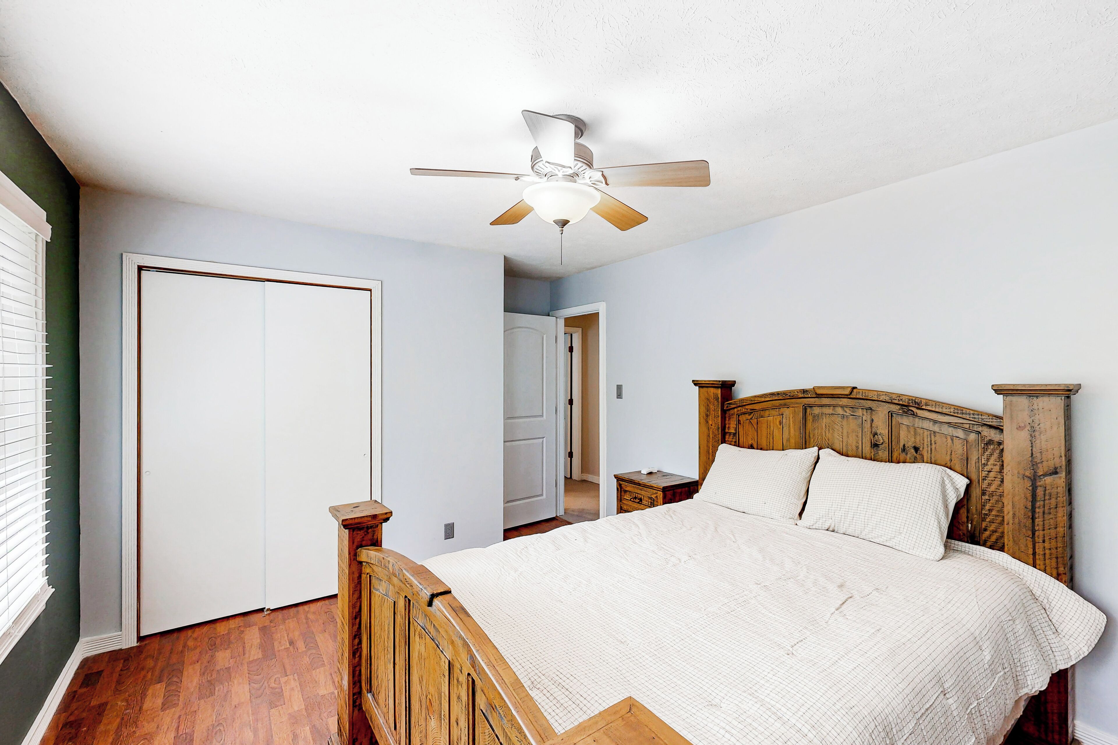 A bedroom with a wooden bed, a ceiling fan, and a white door.