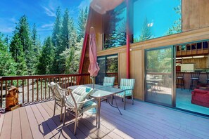 A deck with a table and chairs, a fire hydrant, and a view of trees.