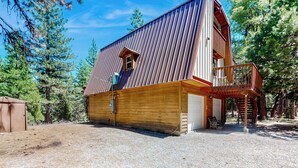 En rustik träladugård med ett tak av metall, en träveranda och ett garage.