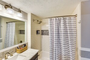 A bathroom with a white sink, a mirror, a shower with a striped curtain, and a towel rack. - Spacious & Family Friendly! Lincoln Home Near Dtwn (Lincoln)