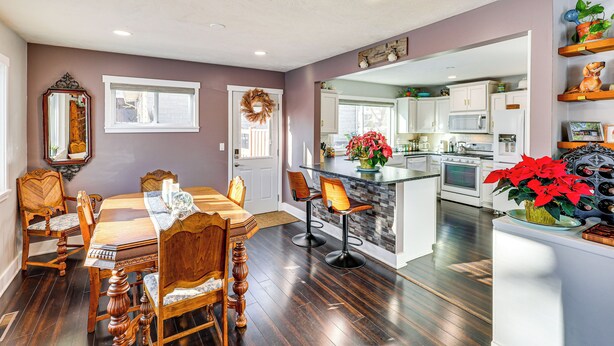 A dining area with a wooden table and chairs, a kitchen with white cabinets, and a small island with a potted plant. - Spacious & Family Friendly! Lincoln Home Near Dtwn (Lincoln)