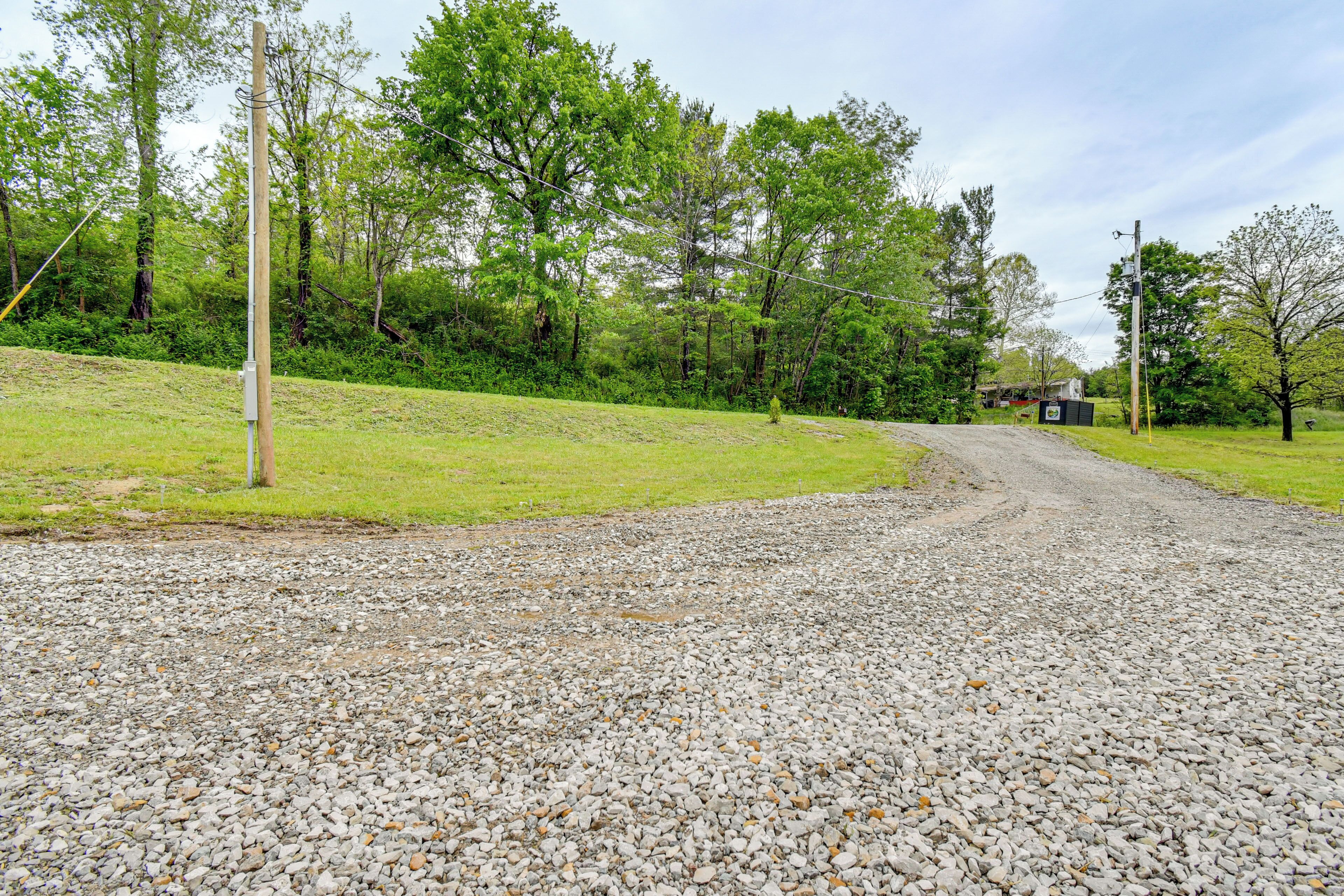 A gravel road curving through a grassy area with trees and a distant building.