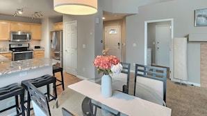 A modern kitchen with stainless steel appliances, a marble countertop, and a dining area with a glass table and black chairs. - Littleton Home w/ Deck - 24 Mi to Denver! (Littleton)