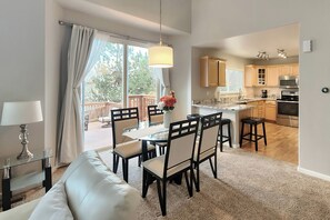 A modern kitchen with wooden cabinets, a stainless steel oven, and a dining area with a glass table and chairs. - Littleton Home w/ Deck - 24 Mi to Denver! (Littleton)