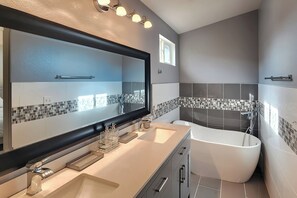 A modern bathroom with a large mirror, dual sinks, a bathtub, and a tiled backsplash. - Littleton Home w/ Deck - 24 Mi to Denver! (Littleton)