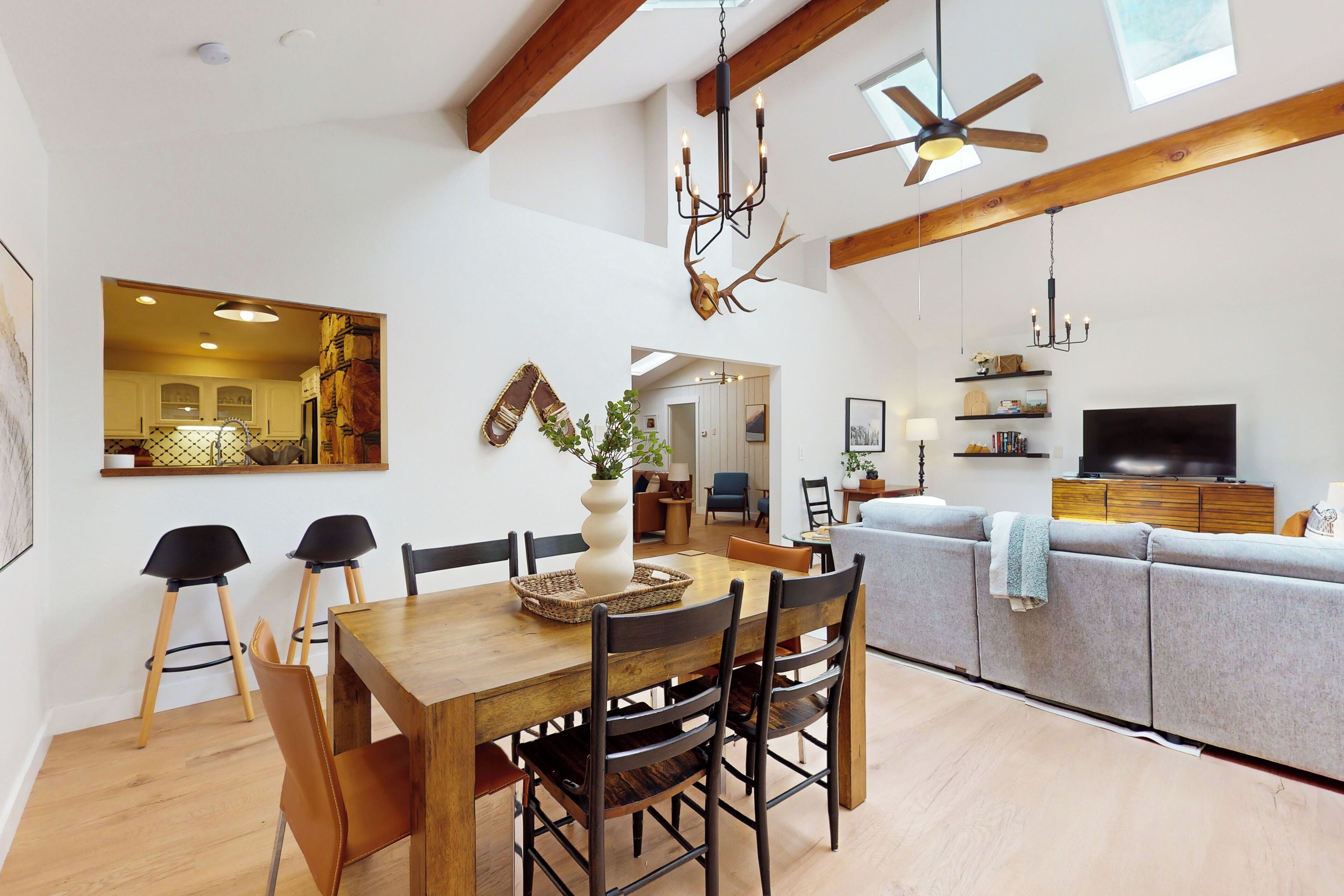 A spacious living area with a wooden dining table, chairs, a sofa, and a television.