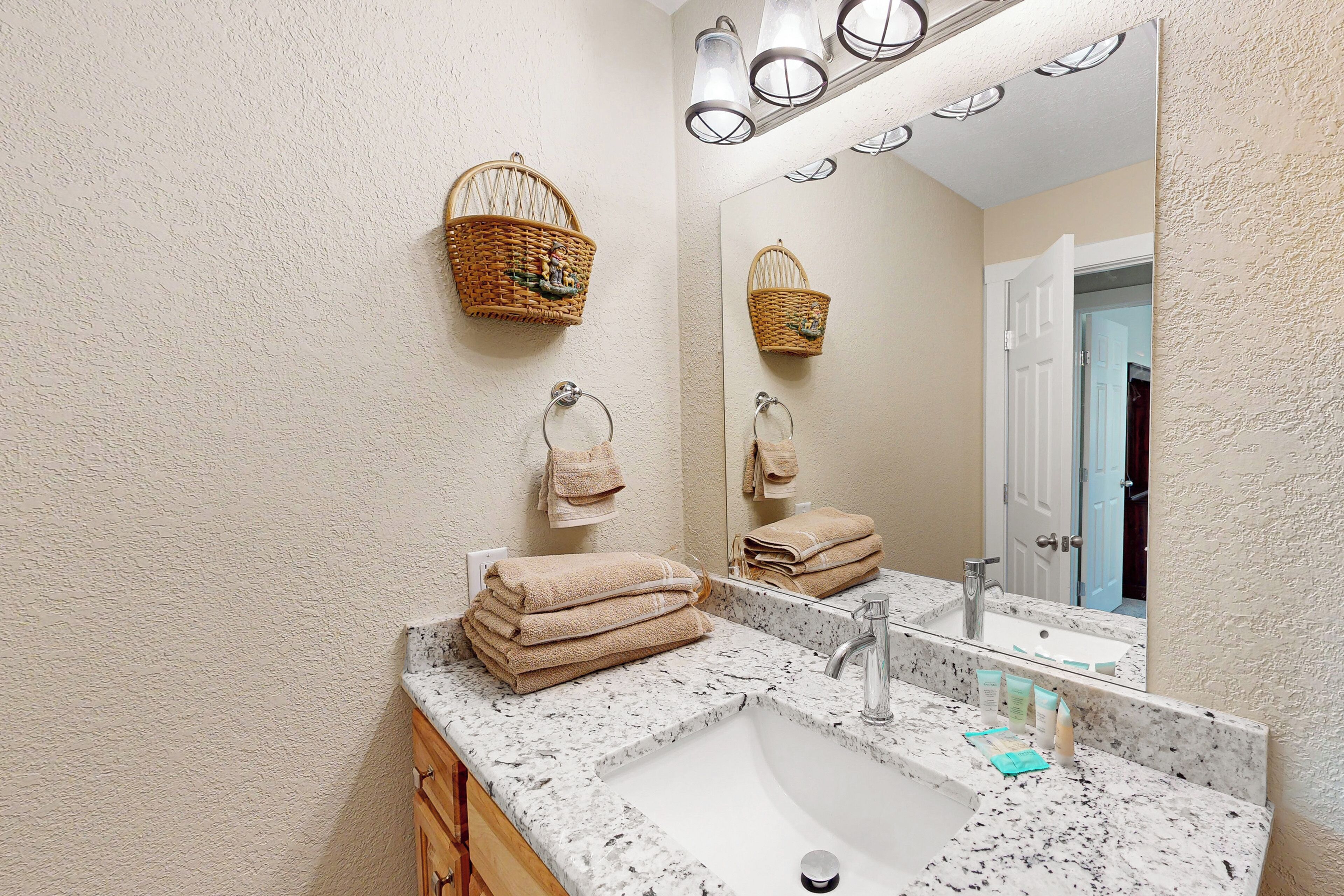 A bathroom with a marble sink, two wicker baskets, and a mirror reflecting the room.