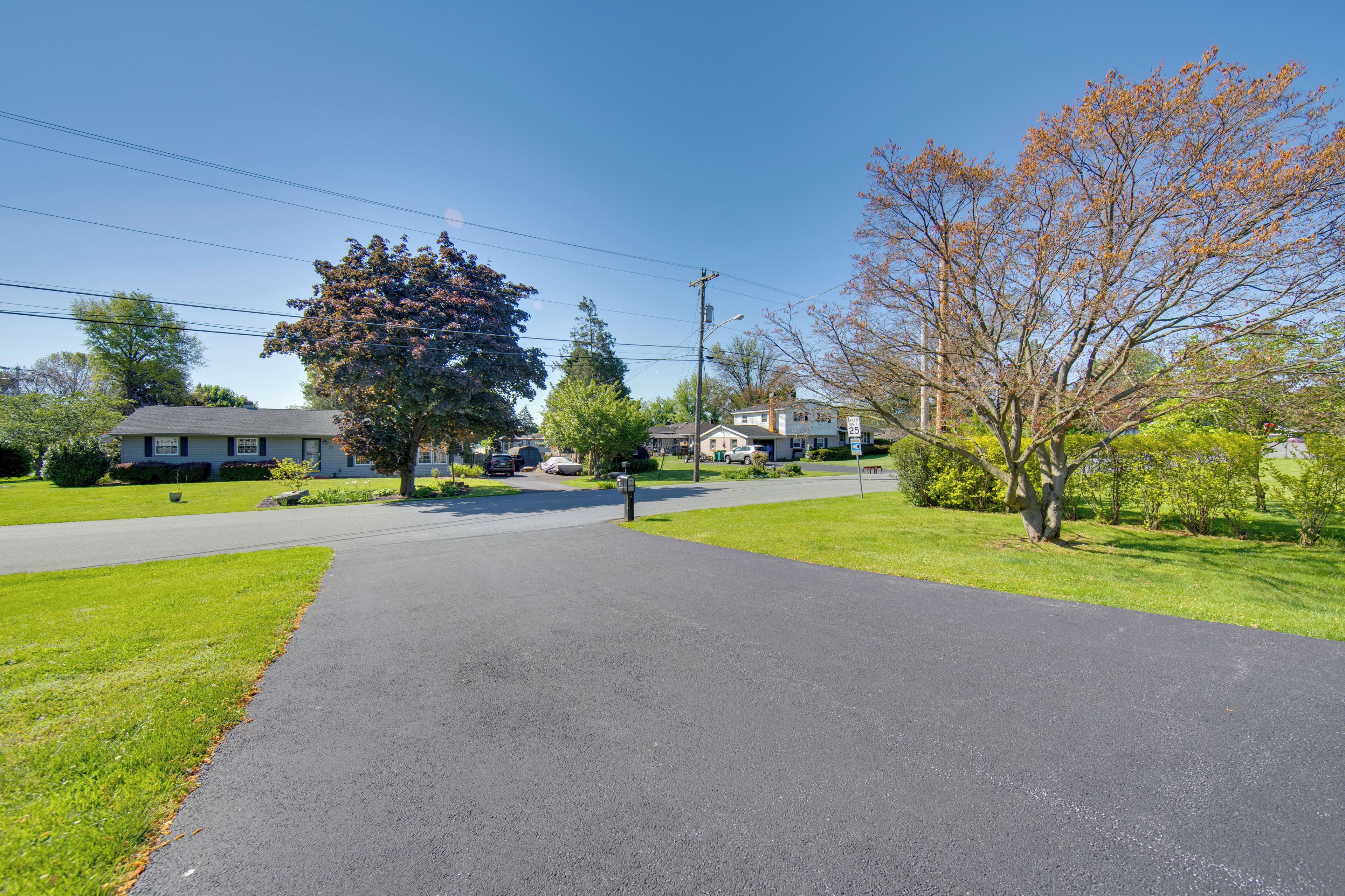 A residential street with houses, a sidewalk, and trees.
