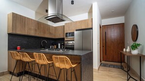 Una cucina moderna con isola centrale, sgabelli da bar, microonde, forno e frigorifero.