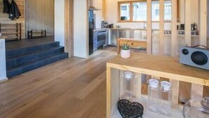 Una cocina moderna con suelo de madera, una isla central con frascos y un banco.