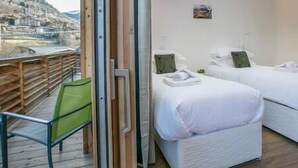 Una habitación con dos camas, una terraza de madera y vistas a un pueblo.