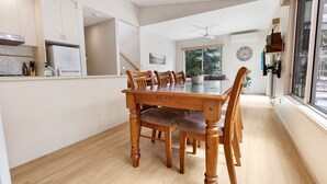 Een moderne keuken met een eettafel en stoelen, houten keukenkastjes en een groot raam.