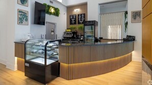 Un área de recepción moderna con una recepción curva, un expositor de vidrio y un televisor montado.