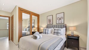 A bedroom with a bed, bedside tables, a mirror, and framed artwork on the wall. - Townhouse Sasha (Almancil)