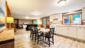 Une cuisine moderne avec un coin repas, un plancher en bois et des meubles de rangement blancs.