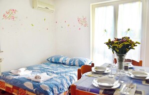 A bedroom with a bed, a table set for dining, and a window with curtains. - Apartment Near the Beach With Garden (Umag)