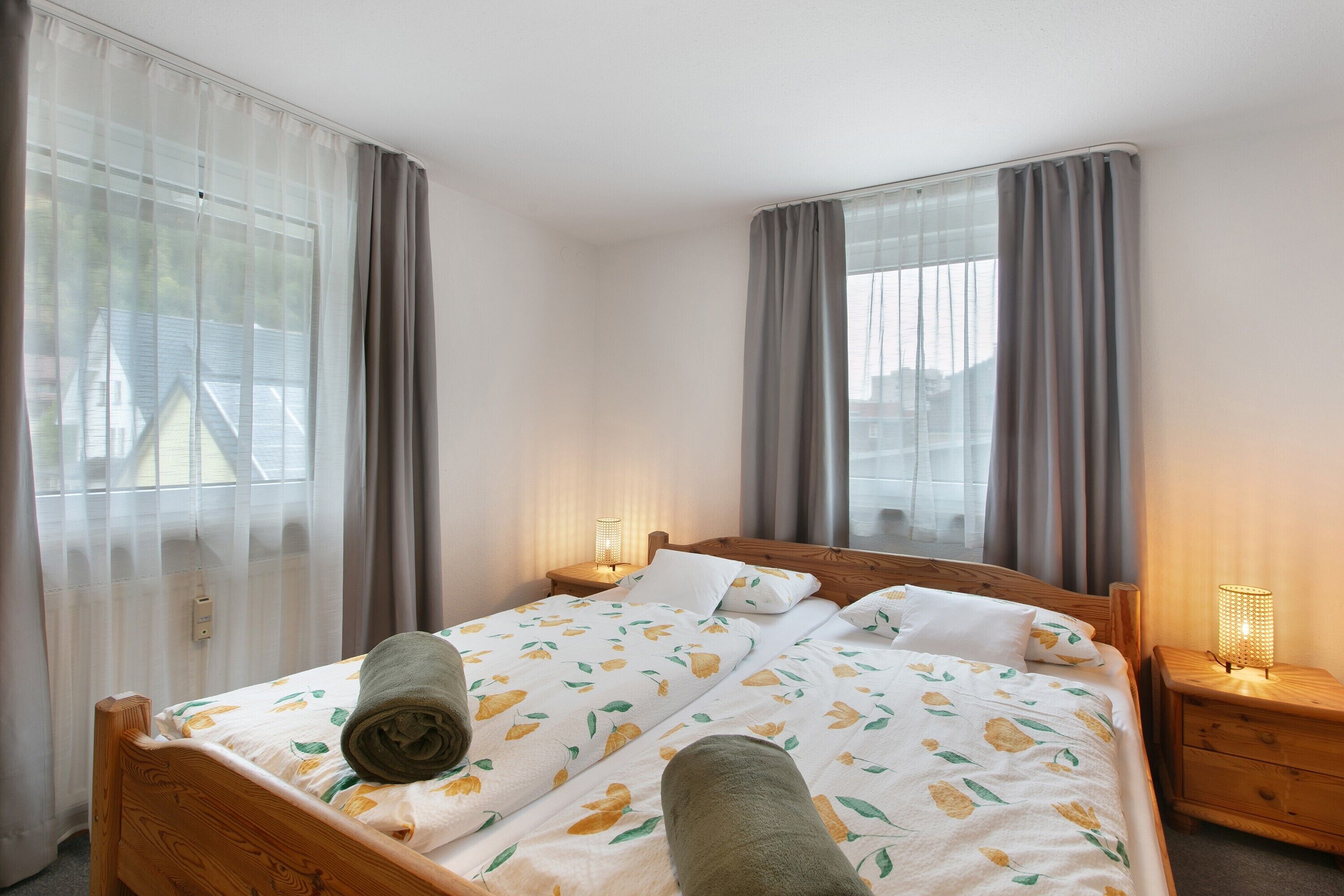 Une chambre d’hôtel avec un lit, deux lampes de chevet et une fenêtre avec des rideaux.