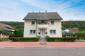 A two-story house with a symmetrical facade, a central entrance, and a small porch with flower boxes. - Apartment in the Cathedral City, Haus Barbara 1st Floor with Mountain View, Terrace & Wi-Fi (St. Blasien)