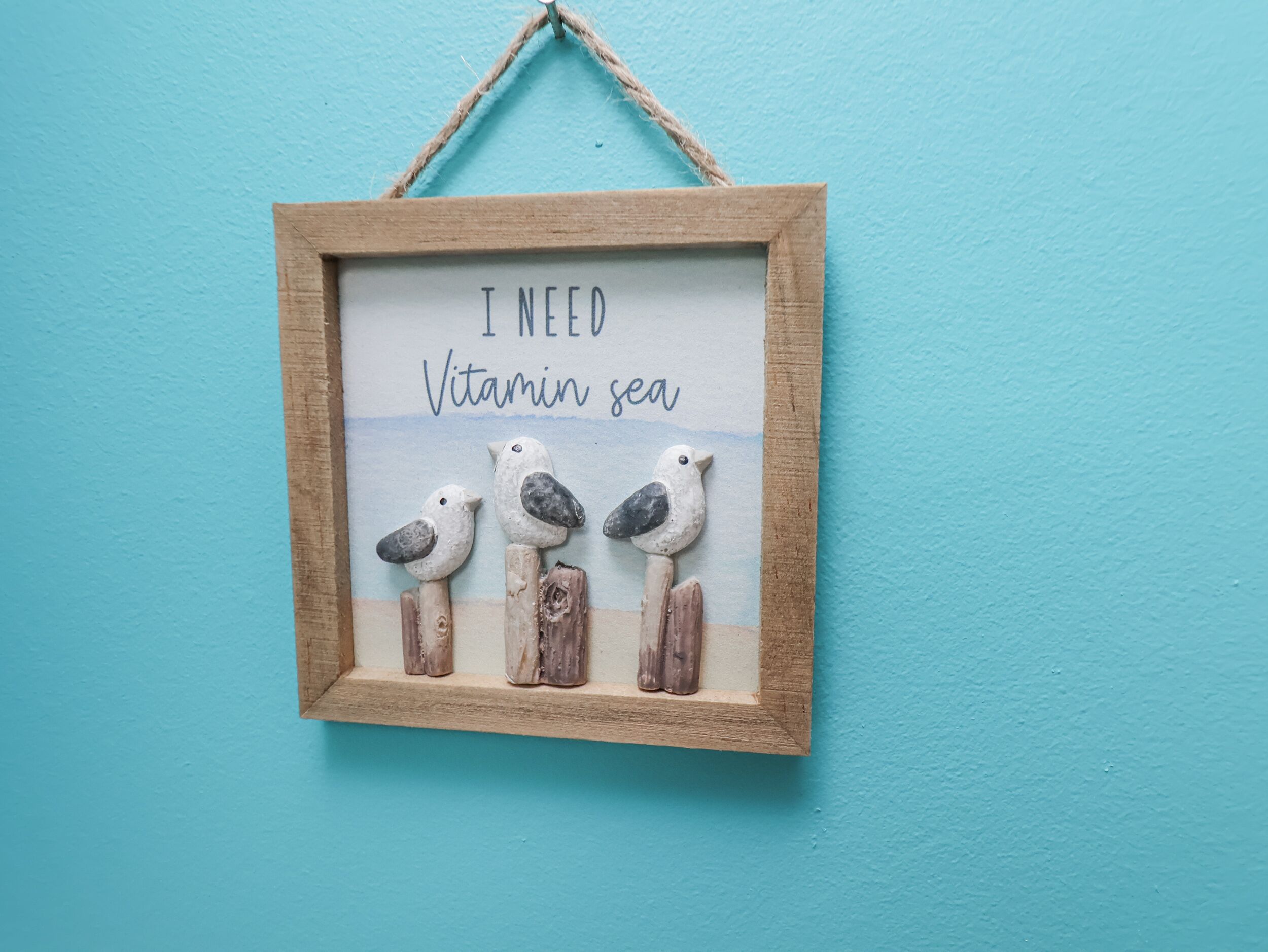 Un panneau encadré avec l’inscription « J’ai besoin de prendre l’air marin » et trois figurines d’oiseaux.