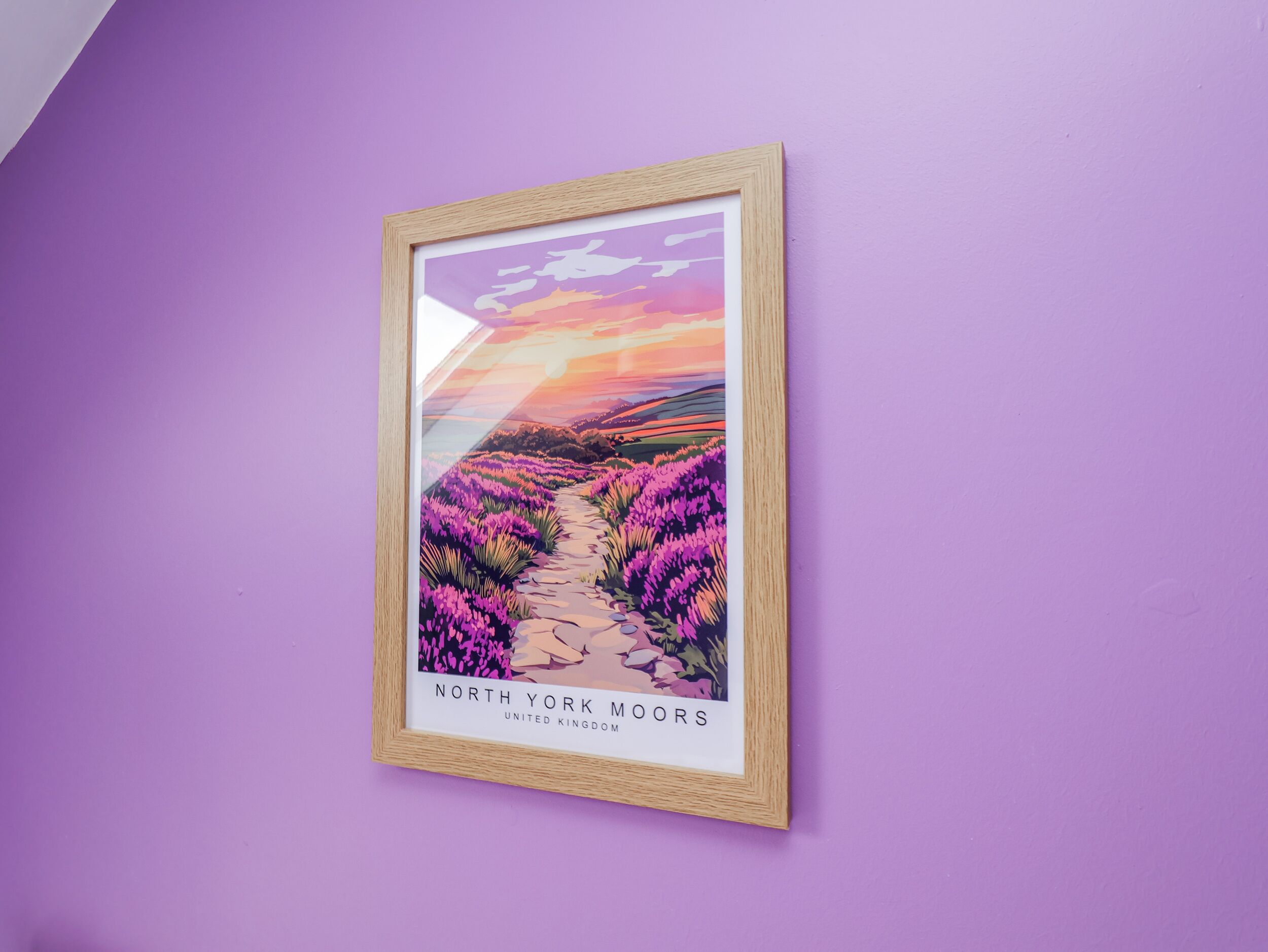 Une œuvre d’art encadrée représentant un paysage violet avec un sentier, intitulée « North York Moors, Royaume-Uni ».