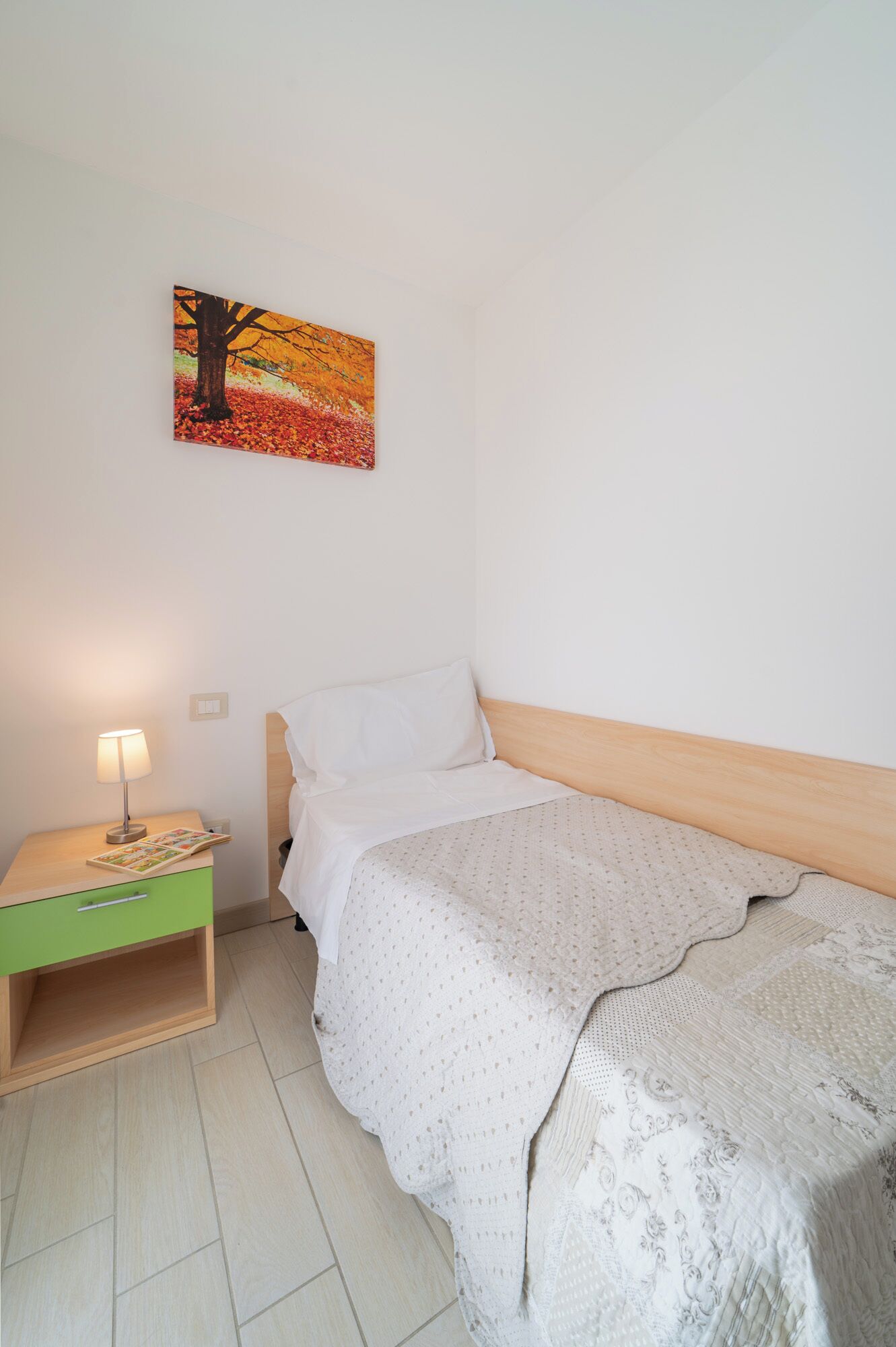 Une chambre à coucher avec un lit, une table de chevet, une lampe et un tableau au mur.