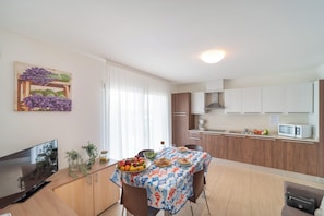 Une cuisine moderne avec des meubles en bois, un four à micro-ondes et un coin repas avec une table dressée pour deux personnes.