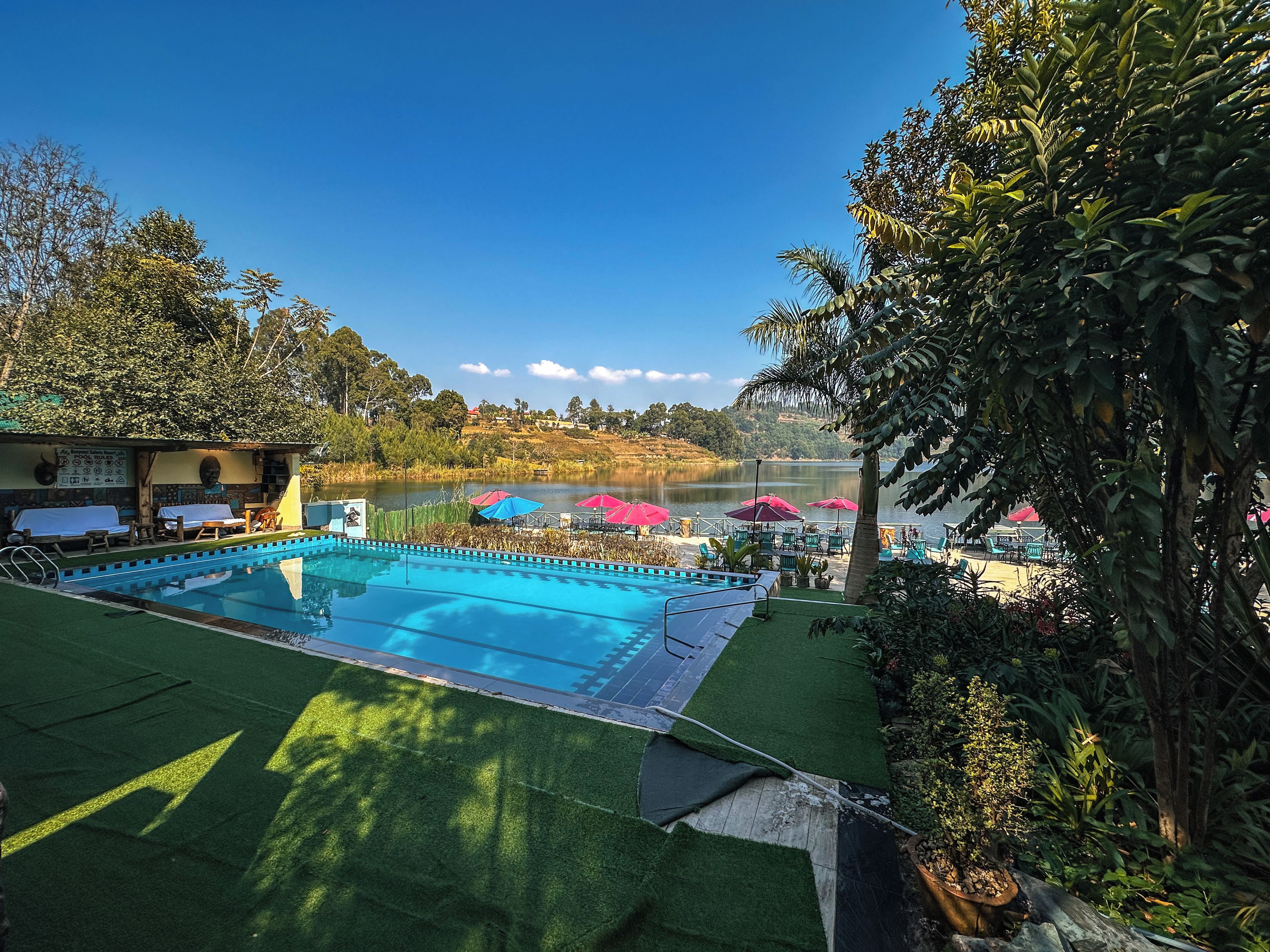 A swimming pool with a view of a lake and hills in the background.