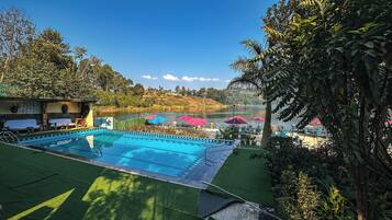 A swimming pool with a view of a lake and hills in the background.