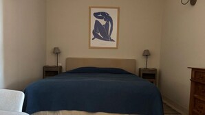 Una camera da letto con un letto grande, due comodini, una sedia e un armadio in legno.