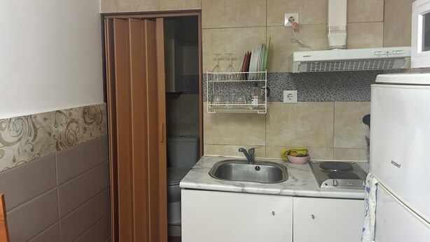 Una cocina compacta con fregadero, estufa y refrigerador.