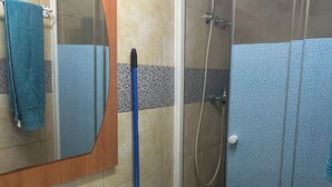 Un baño con lavamanos blanco, espejo, toalla azul y cabina de ducha de vidrio.