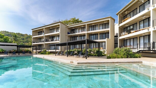 A hotel with a swimming pool, outdoor seating, and multiple balconies. - Short Walk to Beach & Town · Top Level · Solana (Huatulco)
