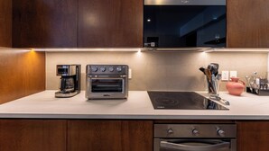 A modern kitchen with wooden cabinets, a built-in oven, a coffee maker, and a flat-screen TV. - Short Walk to Beach & Town · Top Level · Solana (Huatulco)