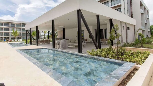 Un hôtel moderne doté d’une piscine, d’un espace extérieur aménagé et d’une terrasse couverte.