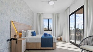 Une chambre d’hôtel moderne avec un lit en bois, une table de chevet avec une lampe, une chaise et une grande fenêtre avec des rideaux.