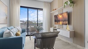 Un salon moderne avec un canapé, un fauteuil et un téléviseur fixé au mur.