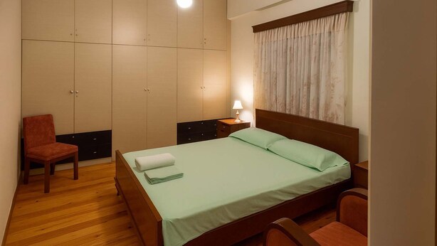 Un dormitorio con cama, una silla, una mesita de noche y un armario.