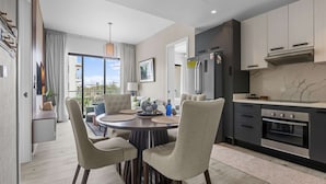 A modern kitchen with dark cabinets, a stainless steel refrigerator, and a built-in oven. - NOK Elegant 2BR Apt by Vistacana (Punta Cana)