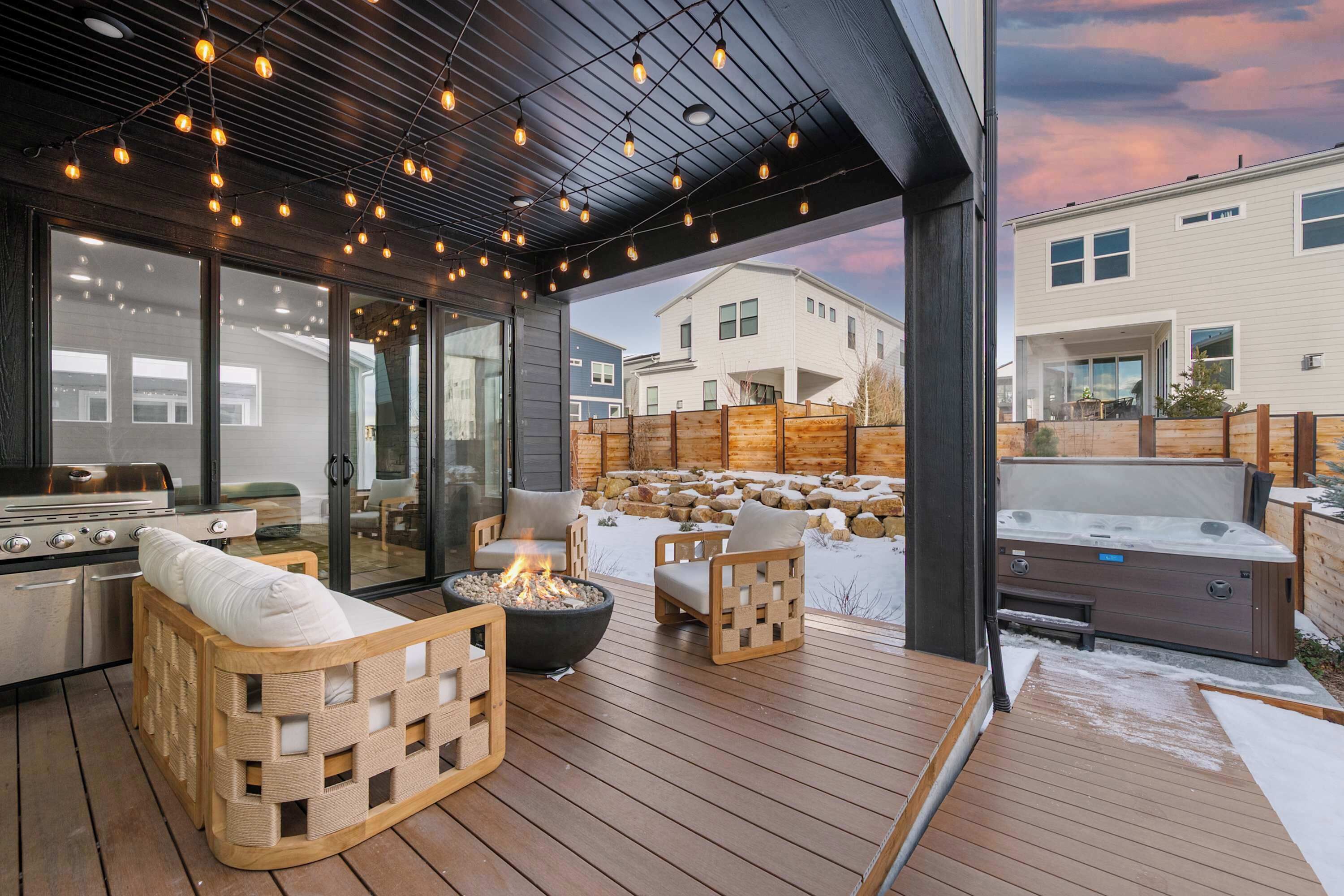 An outdoor patio with wooden furniture, a fire pit, and a hot tub.