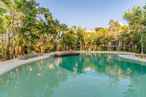 A swimming pool surrounded by trees and lounge chairs. - Anana Yaaxlum 106 S Familly Condo Oasis Pool (Tulum)