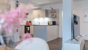 Una cocina moderna con armarios blancos, microondas y cafetera.