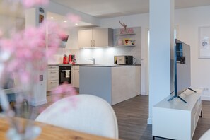 Moderni keittiö, jossa on valkoiset kaapit, mikroaaltouuni ja kahvinkeitin.