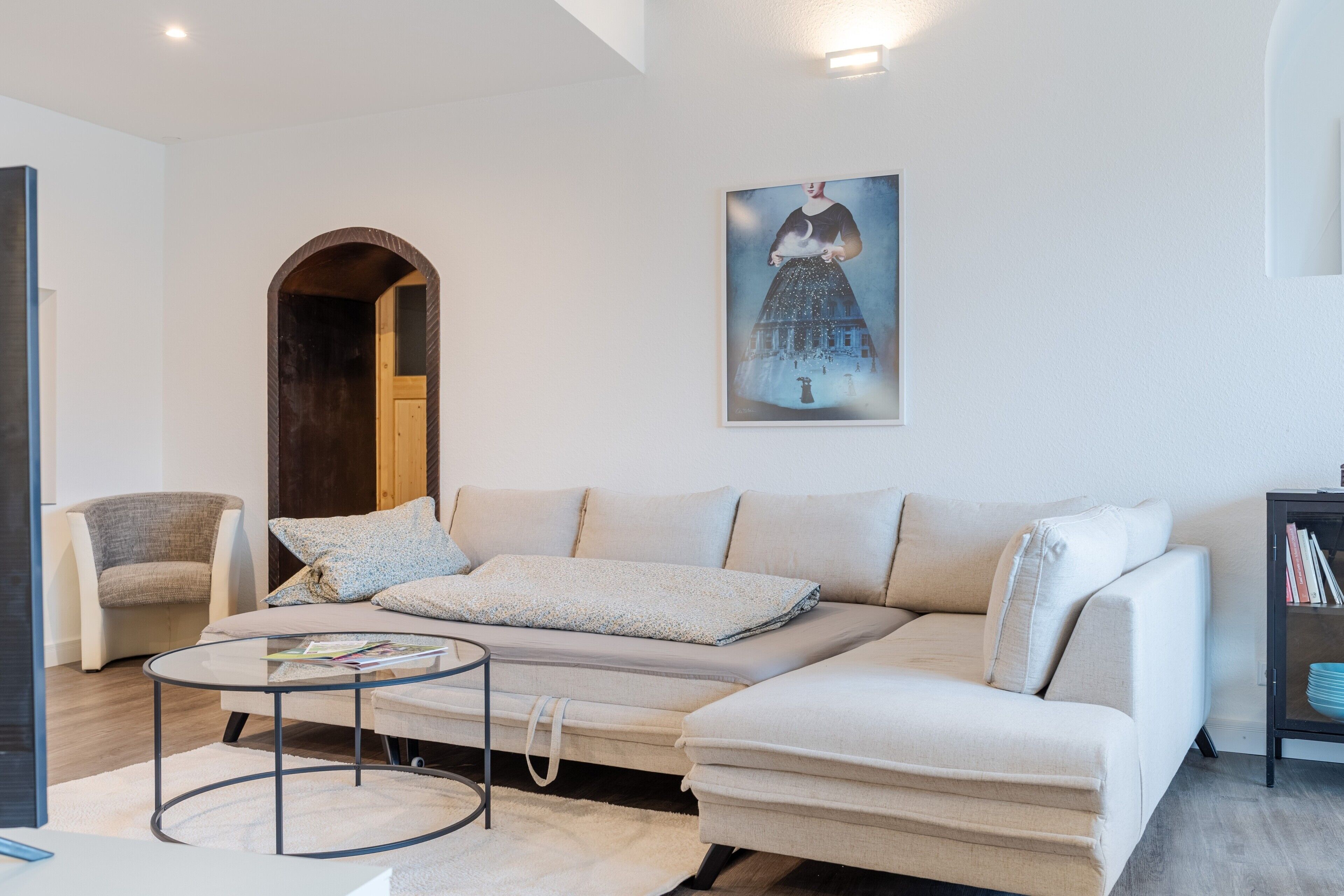 Una sala de estar con sofá, sillón, mesa de centro y un cuadro en la pared.